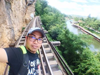 Portrait of man on footbridge against sky