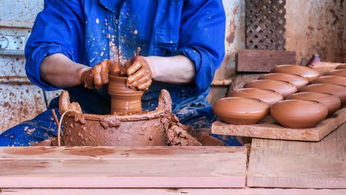 Midsection of man making pot in workshop