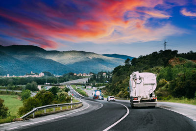 Cars on road against sky during sunset