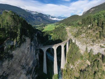 Arch bridge over mountains against sky