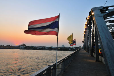 Thai flags waving on metallic bridge over chao phraya river