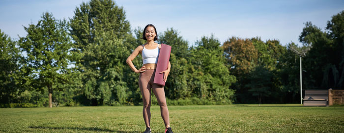 Portrait of young woman exercising on field