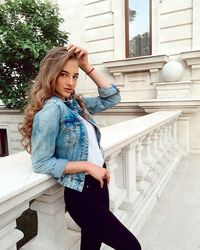 Beautiful young woman standing against wall