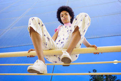 Low section of woman sitting on railing