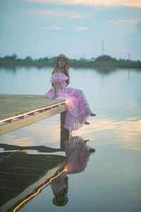 Woman standing in boat on lake against sky