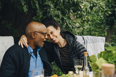 Cheerful senior man and woman enjoying while sitting at dinning table during garden party