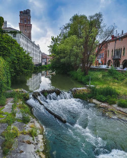 Bridge over river by buildings in city against sky