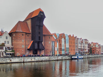 Buildings by river against clear sky