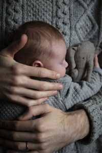 Midsection of father embracing baby at home