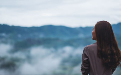 Side view of woman standing against sky