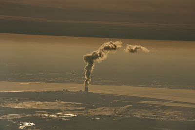 Smoke emitting from chimney on landscape against sky