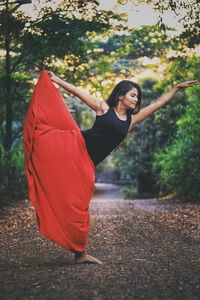 Young woman practicing yoga on road in forest