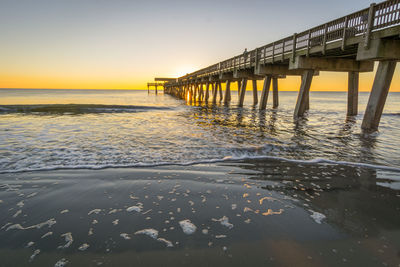 Pier over sea against sky during sunset