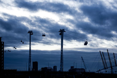 Low angle view of cranes against sky at sunset