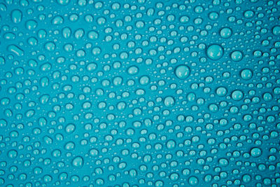 Full frame shot of wet glass against blue background