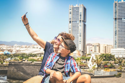 Friends sitting on mobile phone in city