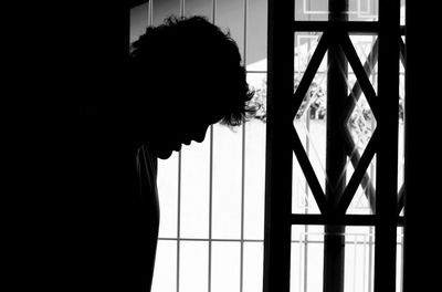 Portrait of silhouette man standing by window at home