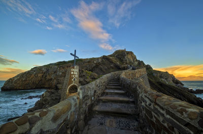 Stone wall by sea against sky