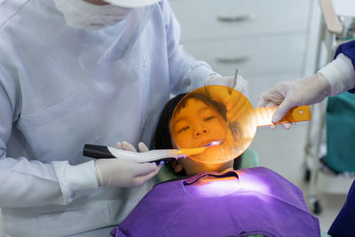 Hand of doctor dentist is working on the teeth of dentist using ultraviolet light on the boy's teeth