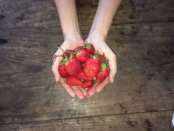 Cropped hands of woman holding strawberries at table
