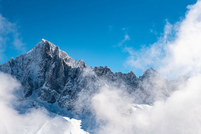 Low angle view of snowcapped mountains against blue sky