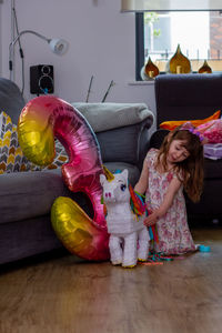 Cute girl with toy sitting on floor at home