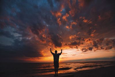 Silhouette woman standing on beach against sky during sunset