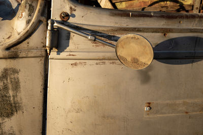 Close-up of old rusty car mirror against side door