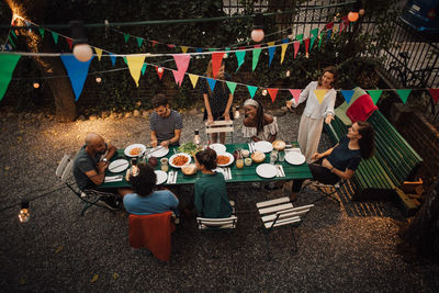 High angle view of multi-ethnic friends enjoying dinner at table during garden party