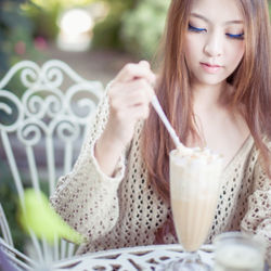 Beautiful young woman drinking milkshake at outdoor restaurant