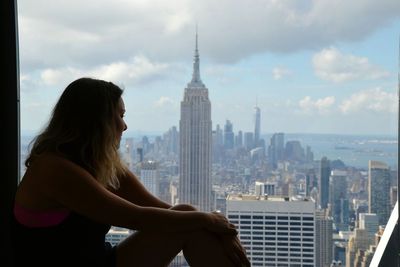 Side view of young woman looking at empire state building in city