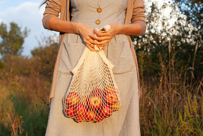 Girl in a dress holding a bag string bag with apples. harvesting. autumn. apple orchard. zero waste 