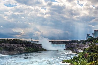 Scenic view of waterfall against cloudy sky