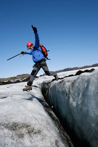 Man jumping over crevasse on the glacier solheimajokull in iceland