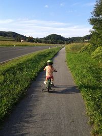 Rear view of woman riding bicycle on road