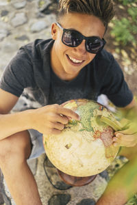 High angle portrait of smiling teenage boy holding globe