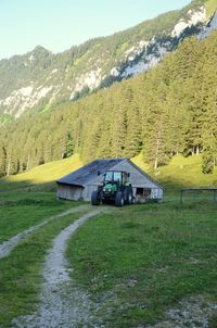 Scenic view of trees and houses on field against mountains