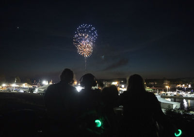 Firework display in city against sky at night