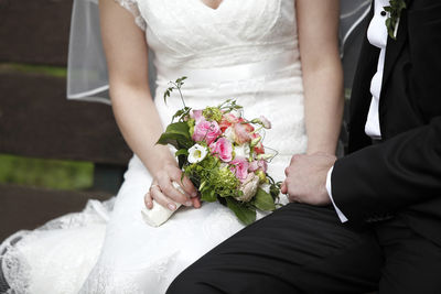 Midsection of bride holding bouquet