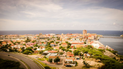 High angle view of cityscape by sea against sky