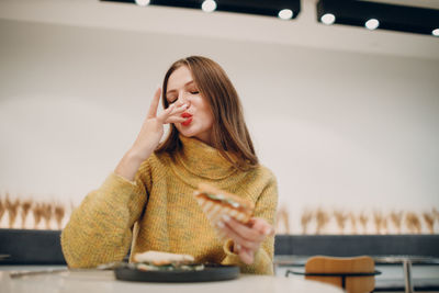 Young woman eating food sitting at cafe