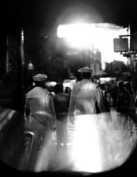 Rear view of people walking on illuminated street at night