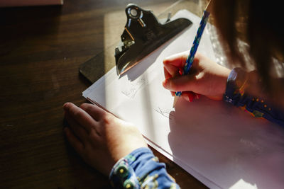 Close-up of a small child sitting in a patch of light doing homework