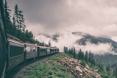 Train by mountain during foggy weather