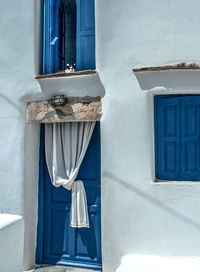 A cat sitting on a window sill of a cycladic traditional house.
