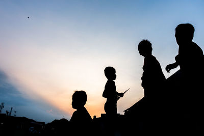 Silhouette people standing against sky during sunset