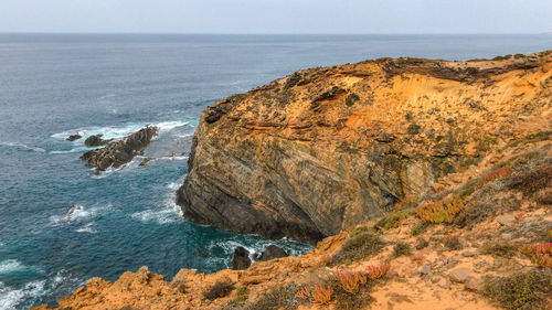 Rock formation on sea shore against sky