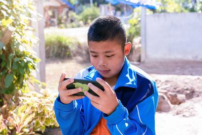 Portrait of child boy playing online games with smartphone, sitting outdoor play with phone in hand 