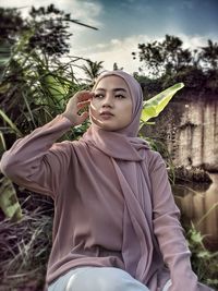 Portrait of smiling young woman standing against trees