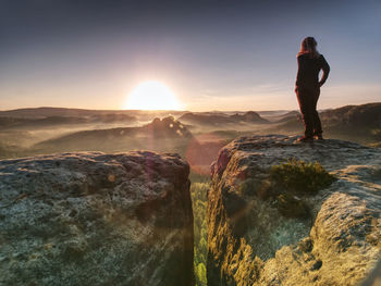 Alone woman hiker model in wild nature within marvelous sunrise. misty valley somewhere in hills